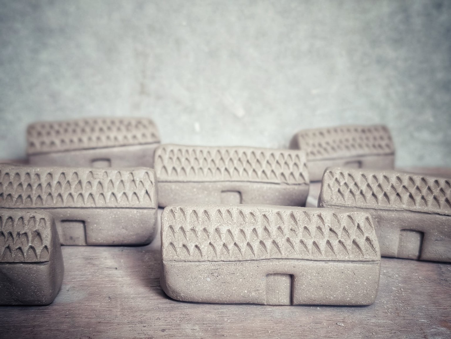 A batch of unfired croft houses lined up in the studio.