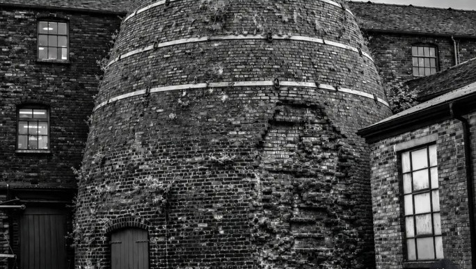 Black-and-white photograph of the bottle kiln and brick buildings at Middleport Pottery