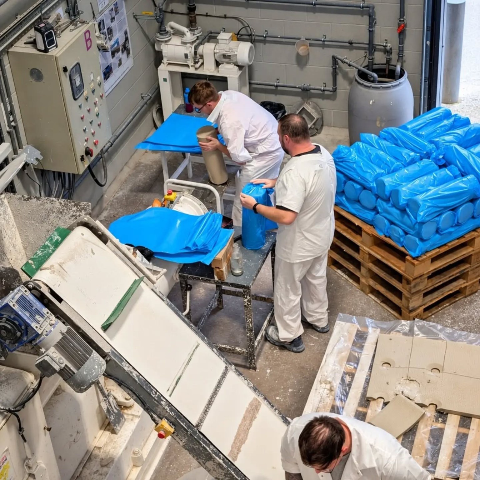 Production floor at Valentine Clays with people handling ceramic material beside processing machinery.