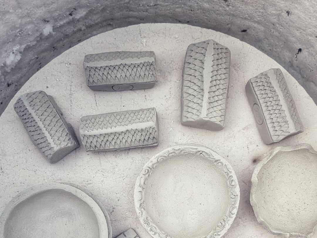 Pale ceramic forms arranged in a kiln before the first firing