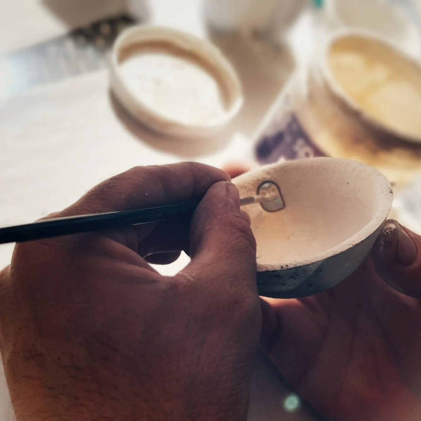 Hand painting glaze detail on an owl bowl before raku firing