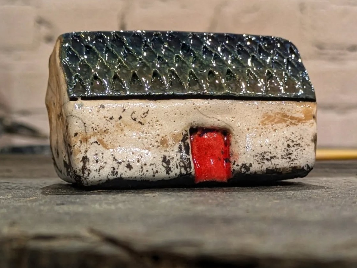 Handmade raku-fired Scottish croft house with dark roof and red door