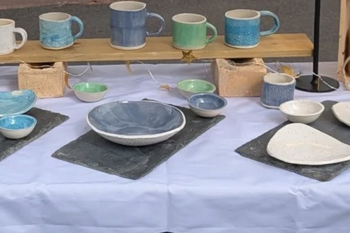 Finished mugs, bowls and plates displayed together at a market.