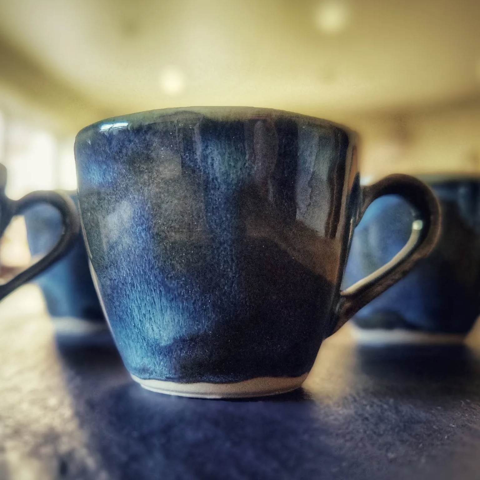 Blue glazed slipcast espresso cup, shown in full with its handle.