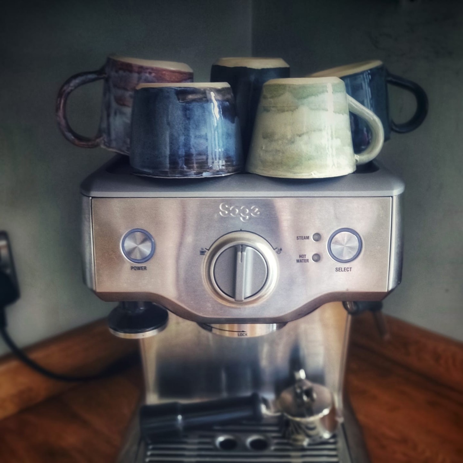 Finished handmade mugs resting on top of a coffee machine, ready for everyday use.
