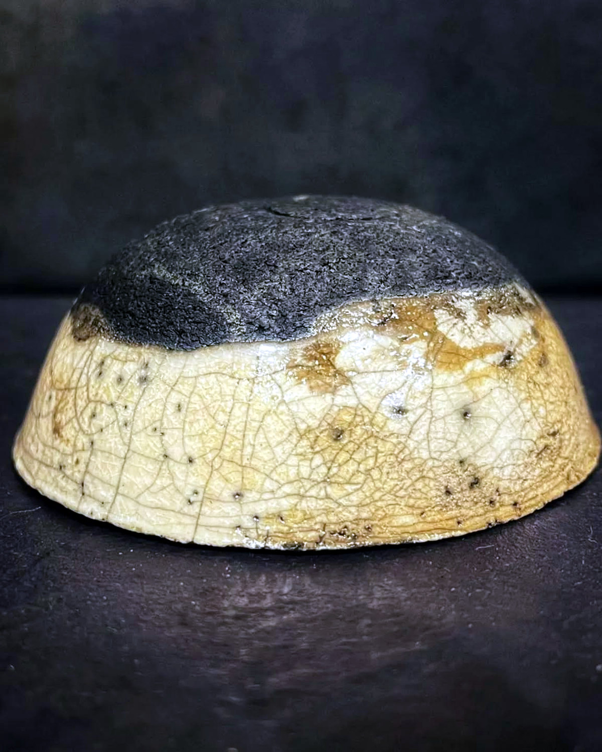 Decorative raku bowl with a pale crackled exterior and a dark smoke-blackened upper surface.